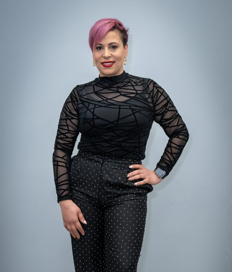 Maribel Aquino, master hairstylist and owner of Divine Beauty Salon and Spa, standing in a black patterned top